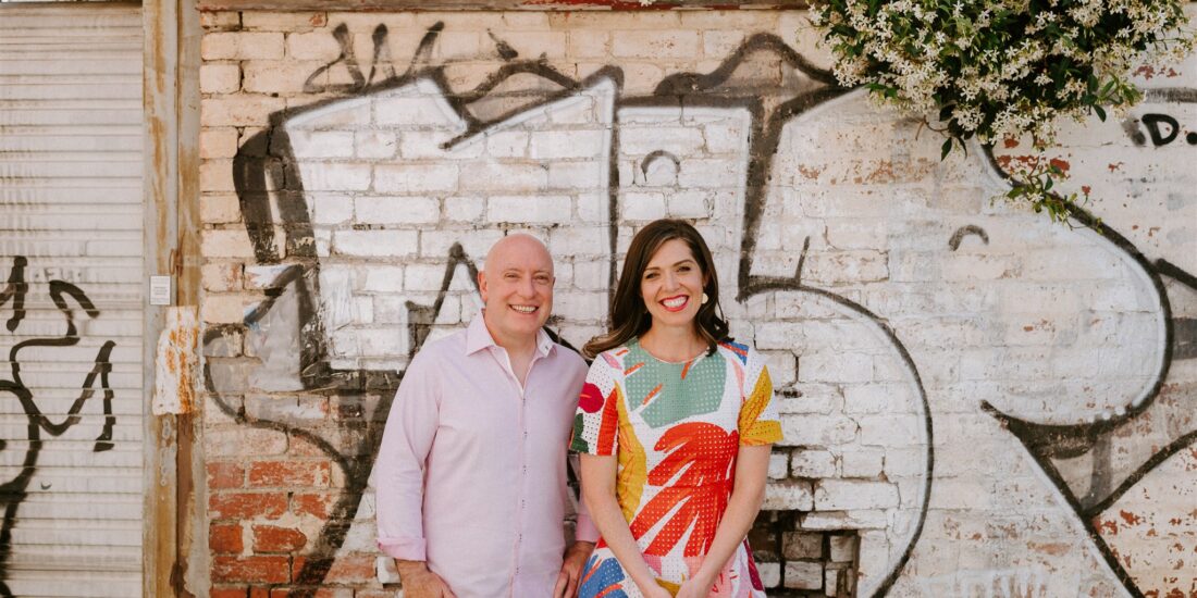 Jason and Sarah stand in a laneway with street art
